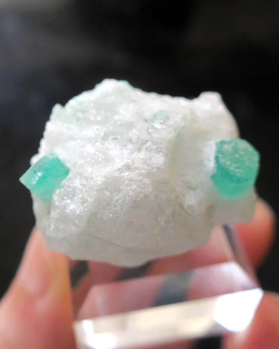 Two emerald crystals on white matrix