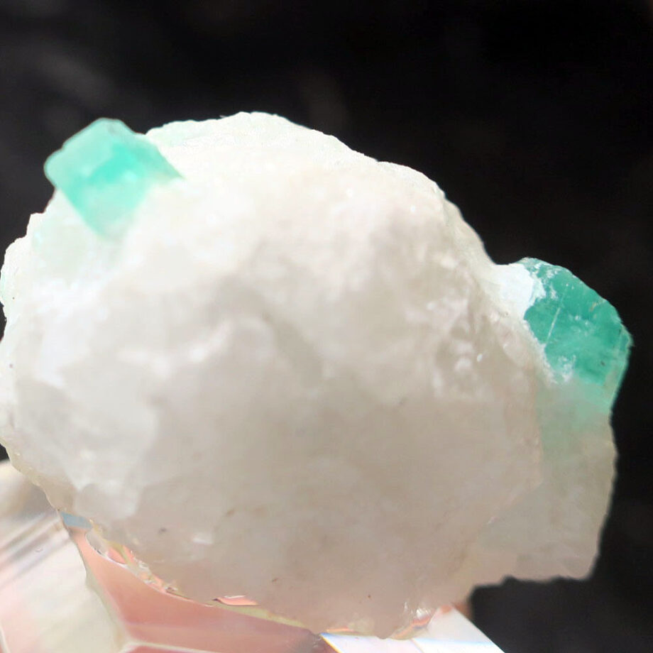 Two emerald crystals on white matrix