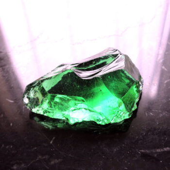 Crystal glass with green bubbles on black table