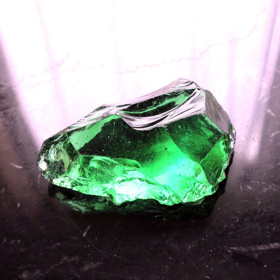 Crystal glass with green bubbles on black table