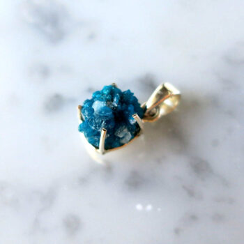 Blue gemstone pendant on white table