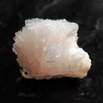 a pink rock on a black surface